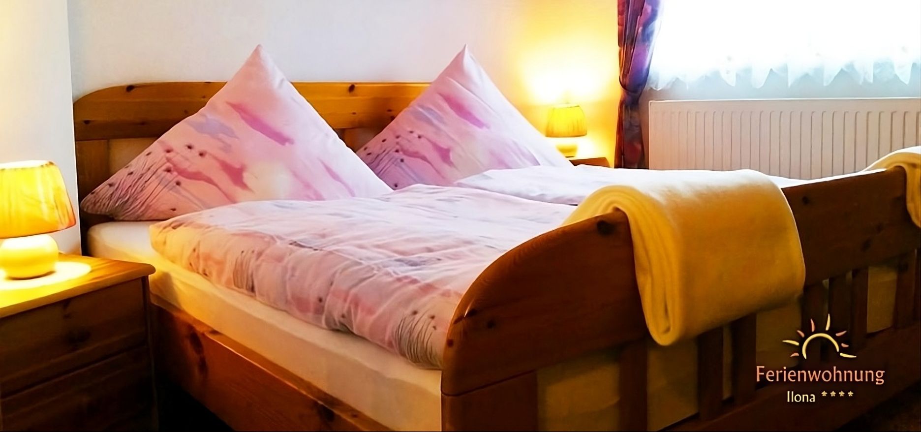 Gemütliches Schlafzimmer der Ferienwohnung Ilona in Zweibrücken mit großem Holzbett, warmem Licht, weichen Bettwaren und freundlicher Wohlfühlatmosphäre.