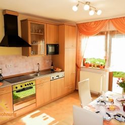 Helle, voll ausgestattete Küche der Ferienwohnung Ilona in Zweibrücken mit moderner Kochzeile, großen Fenstern und liebevoll gedecktem Frühstückstisch – ideal für gemütliche Aufenthalte.